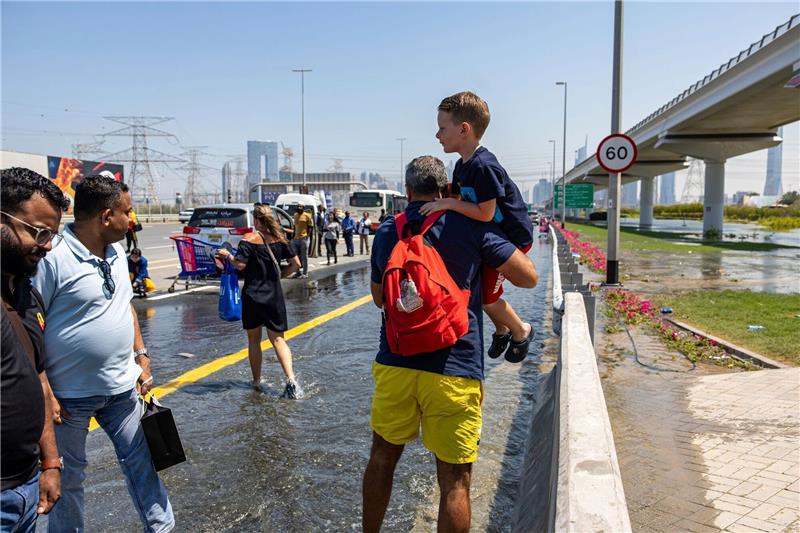 Nach Unwetter in Dubai weiter Störungen am Flughafen Ein Mann trägt ein Kind durch das von starkem Regen verursachte Hochwasser in Dubai.
