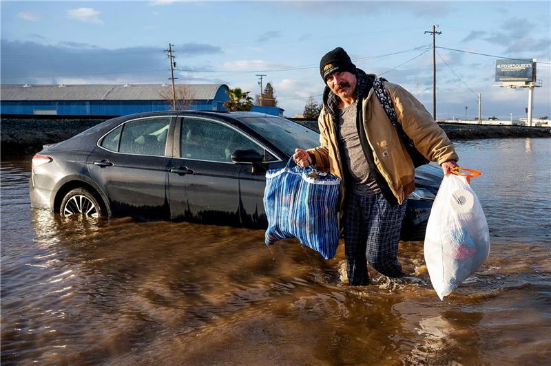 Extremwetter-Jahr: Von Wassermassen und Wirbelstürmen Ein Mann trägt im Januar in Merced, Kalifornien, Habseligkeiten aus seinem überfluteten Haus.