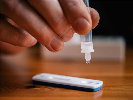 Ein Mann träufelt eine Lösung auf eine Testkassette für einen Schnelltest. Foto: Zacharie Scheurer/dpa/Symbolbild