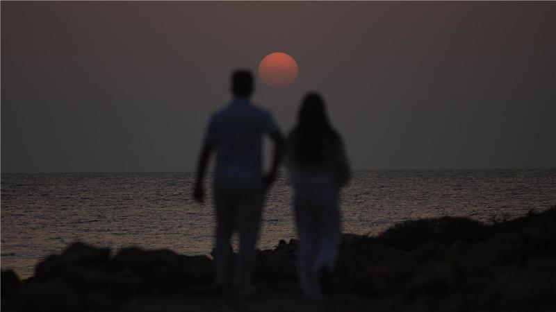 Ein Mann und eine Frau spazieren in der Nähe des Strandes Es Cargol in Santanyi auf Mallorca während des Sonnenuntergangs.
