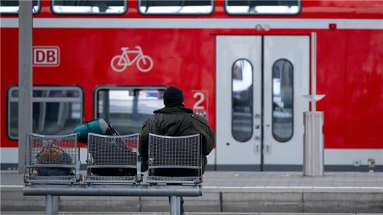 Ein Mann wartet auf einem Bahnsteig am Bahnhof.