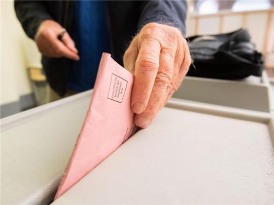 Ein Mann wirft seinen Stimmzettel in eine Wahlurne. Foto: Julian Stratenschulte/dpa/Symbolbild