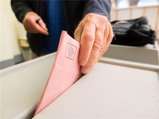 Ein Mann wirft seinen Stimmzettel in eine Wahlurne. Foto: Julian Stratenschulte/dpa/Symbolbild