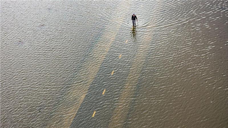Ein Mensch geht auf einem überfluteten Weg während einer Springflut in Kalifornien.