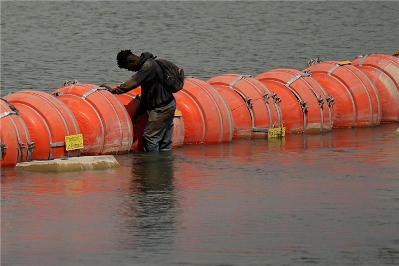 Ein Migrant aus Kolumbien steht an einer schwimmenden Bojenbarriere, um den Rio Grande von Mexiko in die USA zu überqueren.