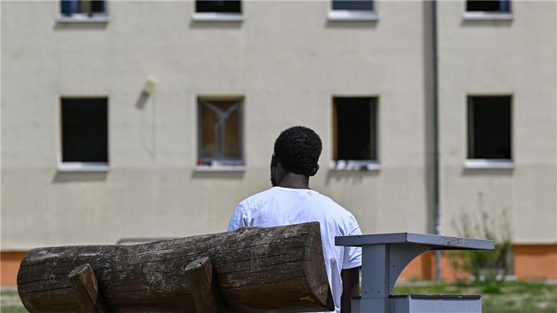 Ein Migrant sitzt auf einer Bank auf dem Gelände der Zentralen Erstaufnahmeeinrichtung für Asylbewerber des Landes Brandenburg in Eisenhüttenstadt. (Archivfoto)