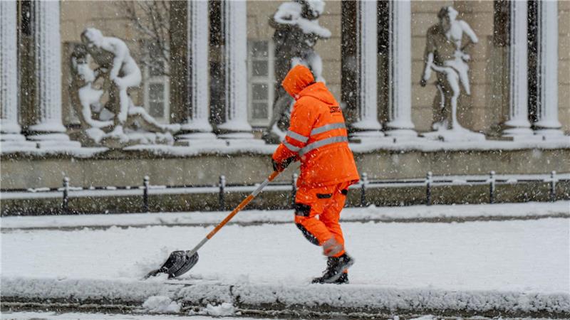 Ein Mitarbeiter der Stadtreinigung Potsdam befreit eine Tram-Haltestelle vom Schnee.