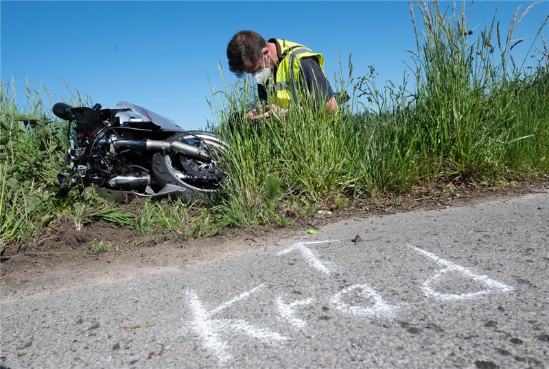 Ein Mann hockt neben einem umgestürzten Motorrad