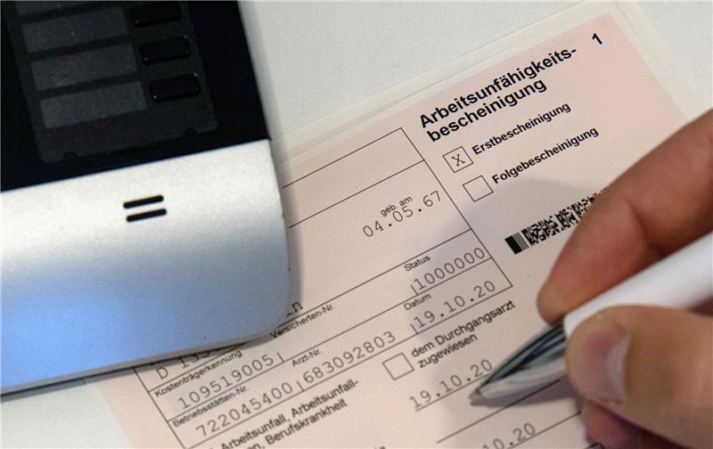 Hausärzte: Erkältungswelle auch bei erwachsenen Patienten Ein Mitarbeiter einer Arztpraxis notiert etwas auf einer Arbeitsunfähigkeitsbescheinigung.