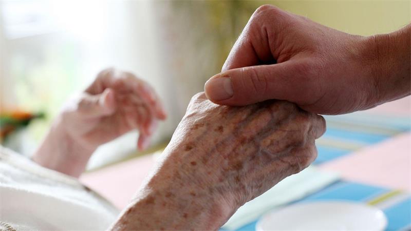 Ein Mitarbeiter eines Alten-und Pflegeheims hält die Hand einer Bewohnerin. (Archivbild)