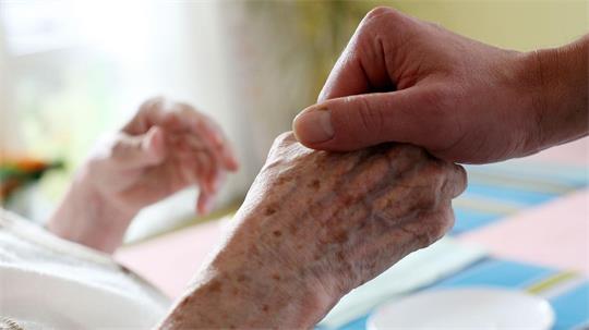 Ein Mitarbeiter eines Alten-und Pflegeheims hält die Hand einer Bewohnerin. (Archivbild)
