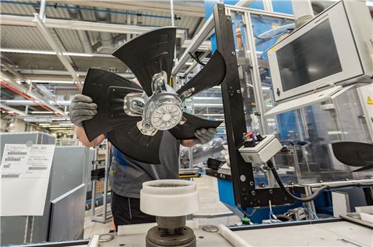 Ein Mitarbeiter eines Herstellers von Ventilatoren und Elektromotoren montiert einen Lüfter.