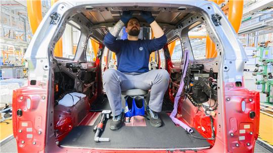 Ein Mitarbeiter montiert einen Elektro-Bulli ID. Buzz im Werk von Volkswagen Nutzfahrzeuge. 