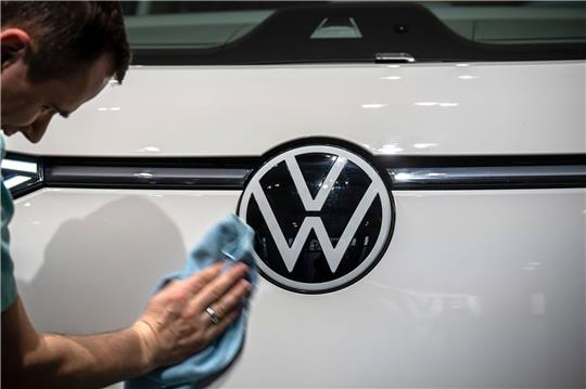 Ein Mitarbeiter poliert vor Beginn der Jahrespressekonferenz das VW-Logo an einem ID. Buzz.