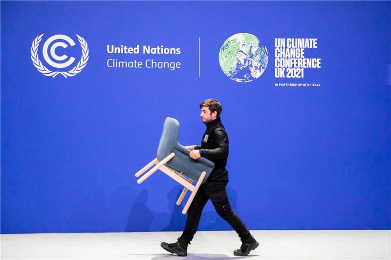 Was aus den Zusagen zum Klimaschutz von Glasgow wurde Ein Mitarbeiter trägt bei der UN-Klimakonferenz COP26 einen Stuhl von einer Bühne.