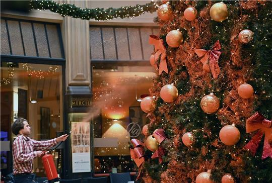 Ein Mitglied der Protestgruppe "Letzte Generation" besprüht einen Weihnachtsbaum in der Leipziger Mädler-Passage.