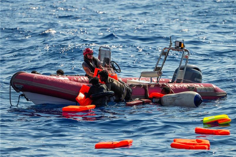Ein Mitglied der spanischen Nichtregierungsorganisation Open Arms hilft Migranten, an Bord zu kommen. Viele Minderjährige sterben während der Flucht.