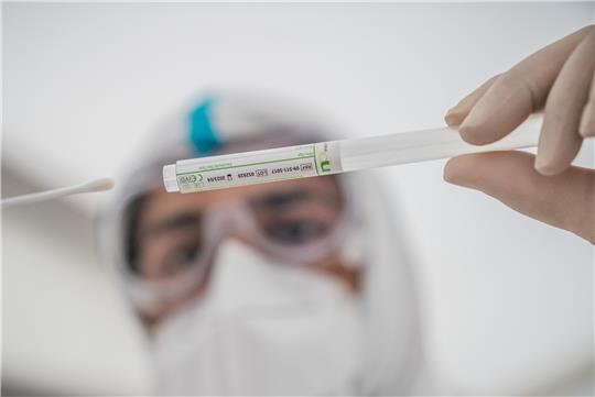 Ein Mitglied des medizinischen Personals in einem Corona-Testzentrum steckt ein Wattestäbchen nach einem PCR-Abstrich zum Test auf Covid-19 in ein Röhrchen (Symbolbild). Foto: Michael Kappeler/dpa