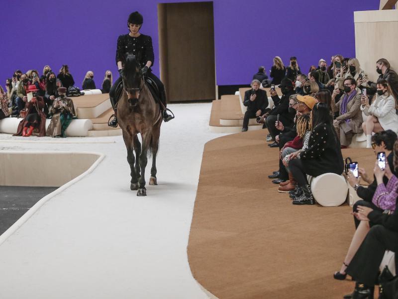 Ein Model reitet auf einem Pferd während der Präsentation der Modekollektion von Chanel für Frühjahr-Sommer 2022. Foto: Lewis Joly/AP/dpa
