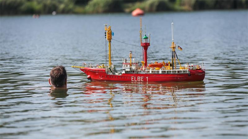 Ein Modellschiff „Elbe 1“ fährt im Schwarzachtalsee an einem Schwimmer vorbei.