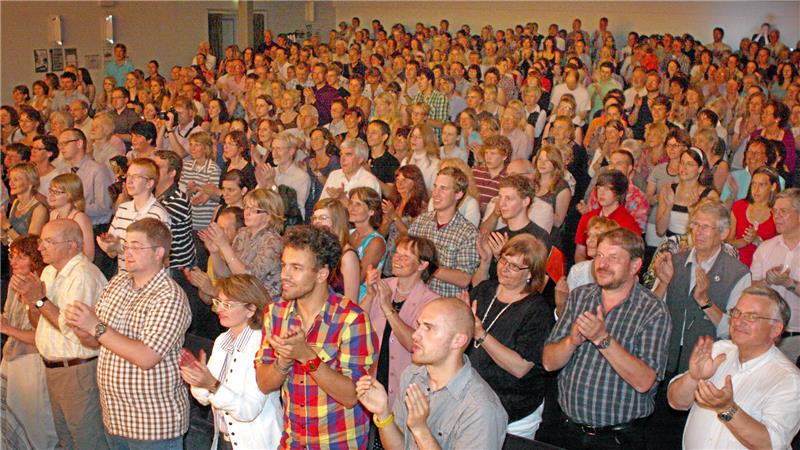 Große Menschenmenge in einem Innenraum, viele klatschen, Gesichter unscharf