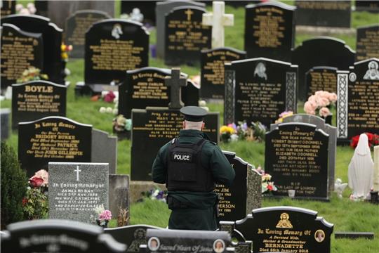 Ein PSNI-Polizist patrouilliert auf dem Stadtfriedhof von Londonderry. Kurz vor der Ankunft von US-Präsident Biden in Nordirland fand die Polizei dort vier mutmaßliche Rohrbomben.