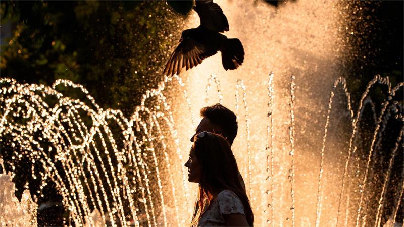 Ein Paar geht an einem Springbrunnen in Bukarest vorbei, während der nationale Wetterdienst für Teile des Landes in den kommenden Tagen eine Hitzewarnung der Stufe „Rot“ herausgegeben hat.