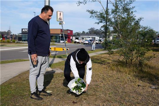 Nach Busunglück mit zehn Toten - Busfahrer freigelassen Ein Paar legt Blumen an einer Straßensperre in der Nähe des Unglücksortes nördlich von Sydney ab.
