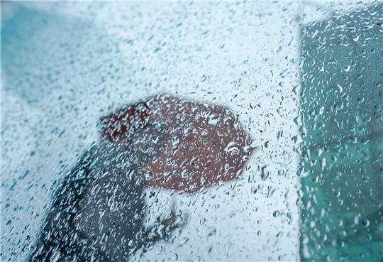 Ein Passant mit Regenschirm.