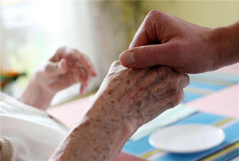 Pflegekräfte fehlen in Bremen mehr als andernorts Ein Pfleger hält in einem Pflegeheim die Hand einer Bewohnerin.