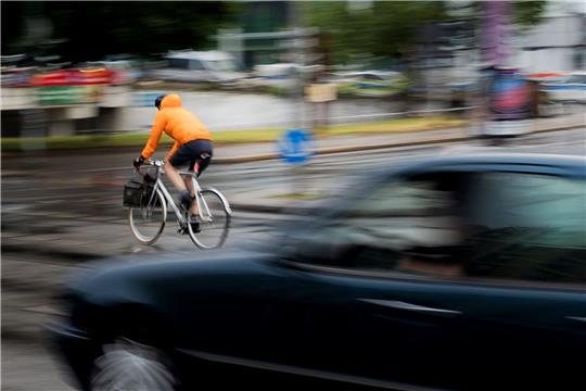 Ein Pkw fährt hinter einem Fahrradfahrer an einer Kreuzung einer Hauptverkehrsstraße in Berlin. Inwieweit Maßnahmen zur Verbesserung der Verkehrssicherheit befürwortet werden, hängt auch stark vom Alter ab.
