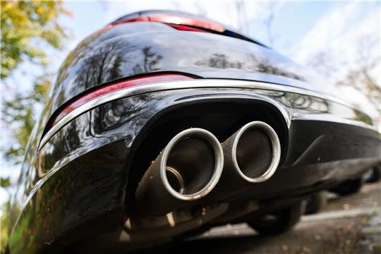 Ein Pkw mit doppeltem Auspuff steht auf einem Parkplatz. Ab 2035 sollen in der EU nur noch Neuwagen verkauft werden, die im Betrieb keine Treibhausgase ausstoßen. Darauf hatten sich Unterhändler der EU-Staaten und des Europaparlaments geeinigt. Foto: picture alliance/dpa | Oliver Berg