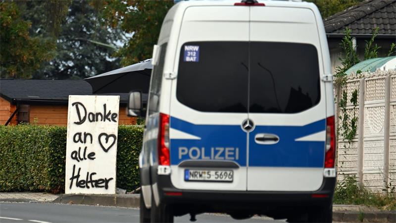 Ein Polizeifahrzeug fährt an einem Schild mit der Aufschrift „Danke an alle Helfer“ vorbei. 