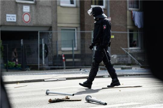 Ein Polizist geht an Metall- und Holzgegenständen vorbei, die vor einem unter Quarantäne gestellten Wohngebäude in der Göttinger Innenstadt auf dem Boden liegen.