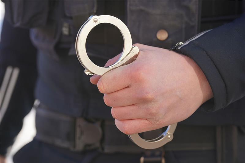 Durchsuchungen in NRW und Niedersachsen: Festnahmen Ein Polizist hält Handschellen in der Hand.
