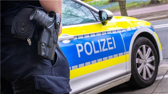 Ein Polizist steht vor einem Polizeiwagen