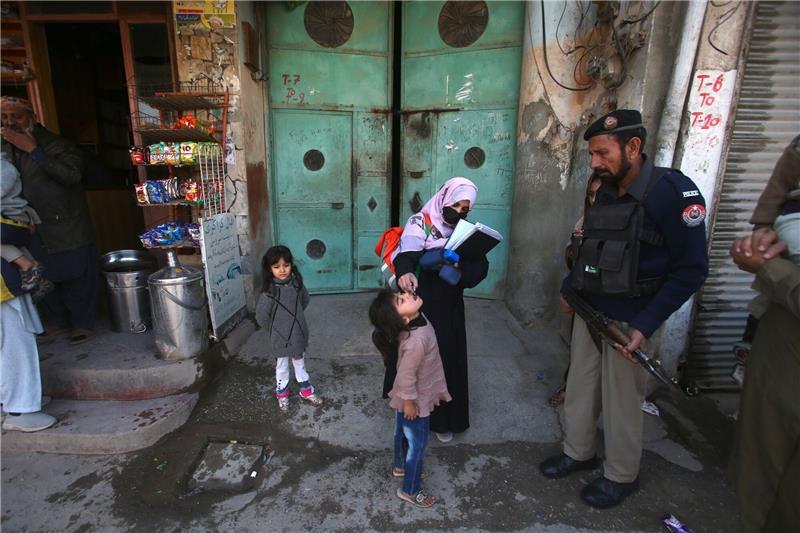 Pakistan meldet ersten Polio-Fall in diesem Jahr Ein Polizist in Pakistan steht Wache, während einem Kind ein Polio-Impfstoff verabreicht wird.