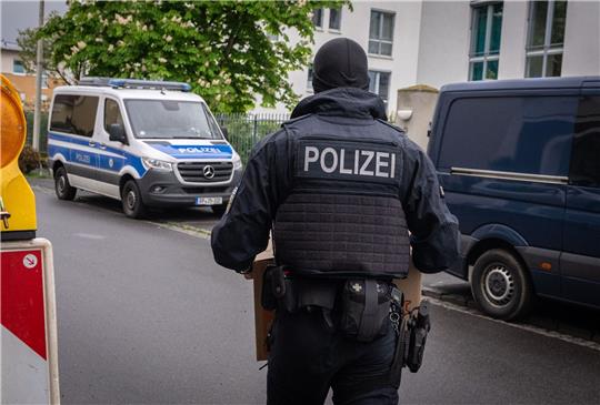 Ein Polizist trägt bei einem Einsatz in Bonn einen Karton mit beschlagnahmtem Material aus einem Gebäude.