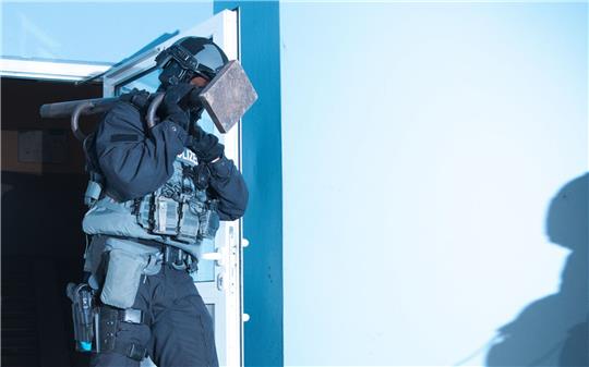 Ein Polizist verlässt bei einer Razzia ein Haus in Berlin.