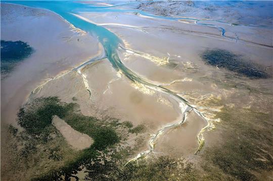Ein Priel zieht sich durch das ostfriesische Wattenmeer.