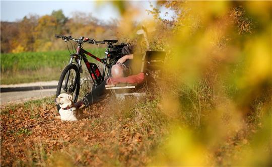 Ein Radfahrer und sein Hund sonnen sich auf der Schwäbischen Alb.