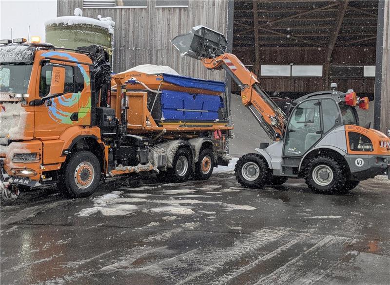 Ein Radlader befüllt einen Lkw mit Streusalz.