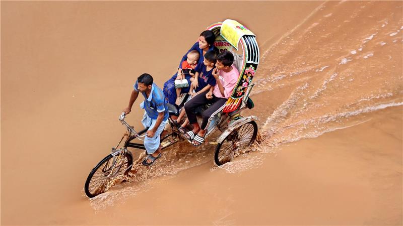 Bilder des Tages Ein Rikschafahrer fährt seine Kunden durch das braune Wasser auf einer überschwemmten Straße in Chittagong in Bangladesch.