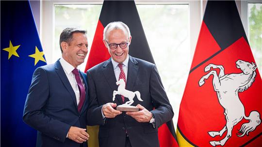 Ein Ross für den Kanzler: Lies (l) überreicht Merz eine Pferdeskulptur – passend zur Krawatte mit Landeswappen-Motiv.