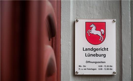 Ein Schild mit Öffnungszeiten hängt am Eingang des Landgerichts Lüneburg.