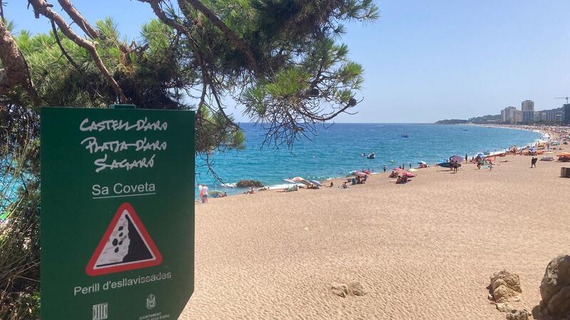 Ein Schild weist an der Platja Gran, dem „Großen Strand“, auf Steinschlag hin.