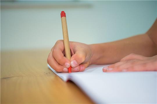 Ein Schüler schreibt mit einem Kugelschreiber in sein Heft.