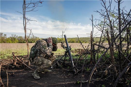 Ein Soldat einer Mörser-Einheit der ukrainischen Streitkräfte hält sich die Ohren zu, während er auf feindliche Stellungen in den Vororten der Stadt Bachmut feuert.