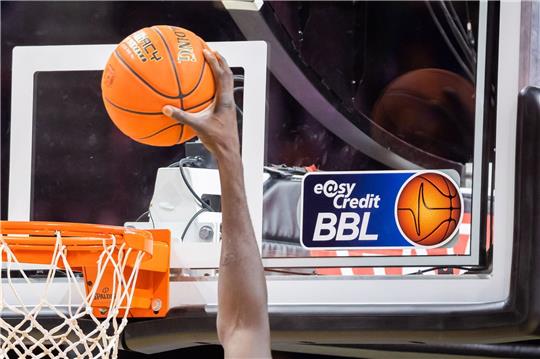 Ein Spieler dunkt, wobei das Logo der Basketball-Bundesliga BBL zu sehen ist.