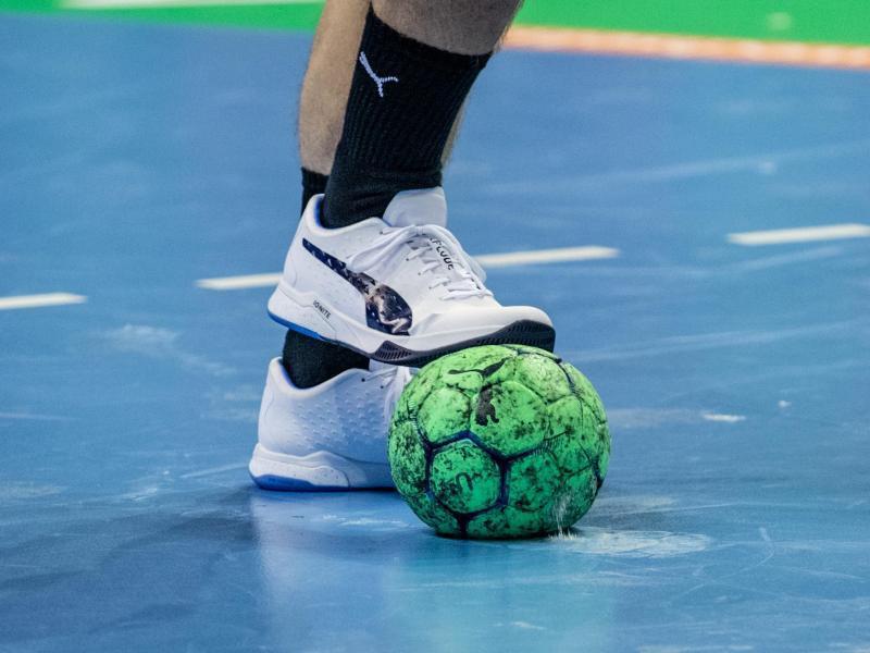 Ein Spieler hält einen Handball mit dem Fuß fest. Foto: Andreas Gora/dpa/Symbolbild